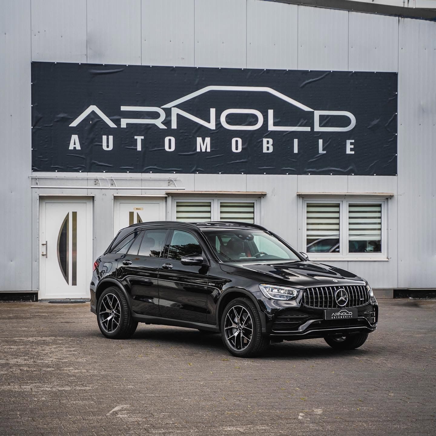 Mercedes-AMG GLC 43 in Schwarz, Frontansicht schräg von rechts vor dem Firmenschild von Arnold Automobile
